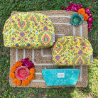 Vibrant Trinity Set of 3 with floral design showing 2 makeup bags and 1 everyday pouch on a natural woven mat.