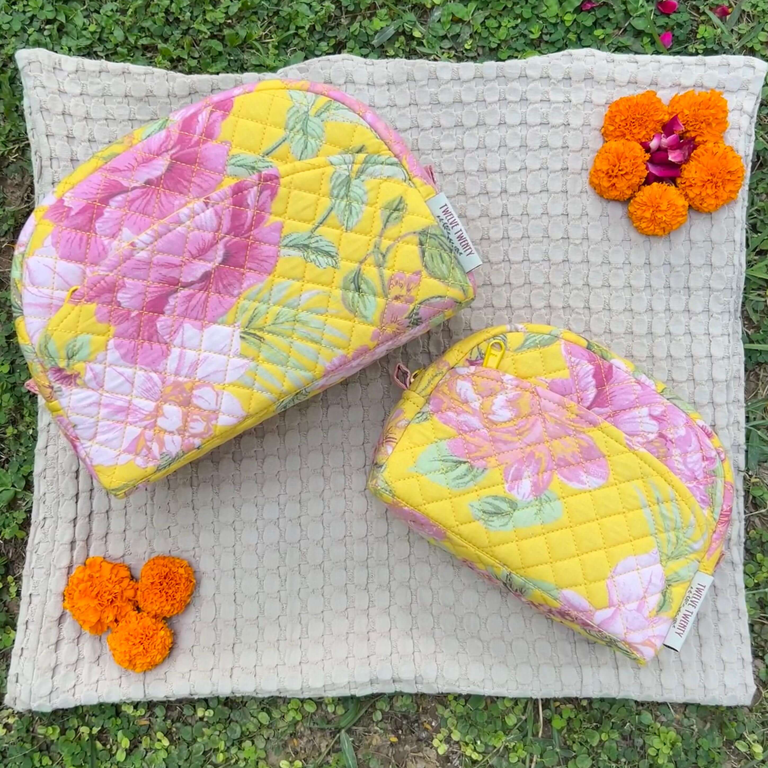 Floral quilted makeup bags set with marigold flowers, featuring large and medium cosmetic pouches on textured fabric background.