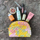 Yellow floral makeup bag set with skincare and cosmetic products on a textured background.