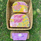 Trinity set of 3 makeup bags and everyday pouch with floral designs, showcasing vibrant colors in a woven basket.